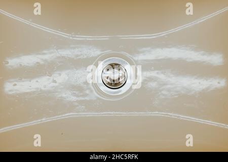 Blick von oben auf ein cremefarbenes Keramikwaschbecken mit leuchtenden Lampen Stockfoto