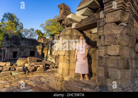 Ein Mädchen in den Ruinen des Ta Prohm Tempels im Angkor Komplex, von Bäumen überwuchert, Kambodscha Stockfoto