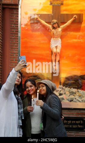 Neu-Delhi, Indien. 24th Dez 2021. Junge Mädchen machen am Vorabend von Weihnachten Selfie vor der Kirche des Heiligen Herzens, da sich die Kirchen schließen, als Vorsichtsmaßnahme gegen die Verbreitung von Covid-19. Die Regierung von Delhi kündigte ein Verbot von kulturellen Veranstaltungen und Versammlungen von Gemeinden an, um das bevorstehende Weihnachts- und Neujahrsfest zu feiern. Kredit: SOPA Images Limited/Alamy Live Nachrichten Stockfoto