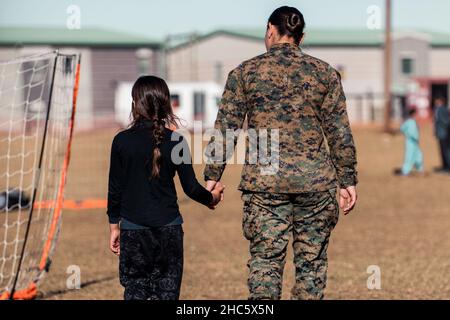 Fort Pickett, Virginia, USA. 14th Dez 2021. Sgt. Amanda Claro-Bevsek mit der 3rd Civil Affair Group, Force Headquarters Group, Marine Forces Reserve führt einen afghanischen Evakuierten am 14. Dezember 2021 durch ein Fußballfeld in Fort Pickett, Virginia. Sgt. Claro-Bevsek meldete sich freiwillig als Teil der Task Force Pickett, um ihre Fähigkeiten in eine reale Anwendung zu integrieren, in der sie helfen kann, das Leben von Menschen zu verbessern, die weniger glücklich sind als sie selbst. Das Verteidigungsministerium stellt durch das Northern Command der USA und zur Unterstützung des Heimatschutzministeriums Transport, vorübergehende Unterbringung, mich, zur Verfügung Stockfoto