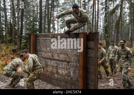 Grafenwoehr, Bayern, Deutschland. 14th Dez 2021. Fallschirmjäger der US-Armee, die 1st Squadron, 91st Kavallerieregiment, 173rd Airborne Brigade zugewiesen wurden, springen während des Hindernisparcours-Teils einer Spornfahrt auf dem Trainingsgelände des 7th Army Training Command in Grafenwoehr, Deutschland, 14. Dezember 2021, über eine Wand. Der Zweck dieser Spornfahrt ist es, neue Fallschirmjäger in die Luftgetragene Kavallerie zu integrieren und innerhalb der Staffel einen Esprit de Corps aufzubauen, der sich auf das Erbe der Kavallerie konzentriert. Kredit: U.S. Army/ZUMA Press Wire Service/ZUMAPRESS.com/Alamy Live Nachrichten Stockfoto