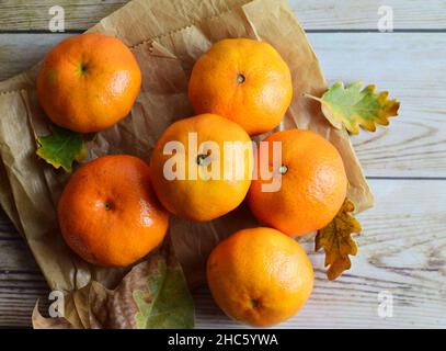 Draufsicht auf frische Mandarinen und Blätter auf einer Holzfläche Stockfoto
