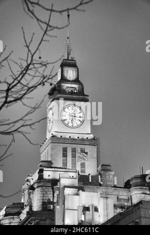 Schwarz-Weiß-Vintage-Foto von trockenen Ästen und der alten Big Clock auf einem hohen Turm im Shanghai Custom House, China im Winter Stockfoto