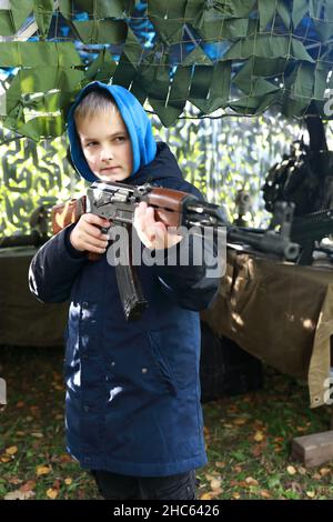 Kind zielt mit Maschinengewehr im Park Stockfoto