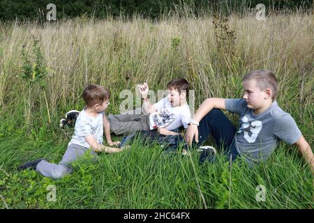 Drei Kinder, die im Sommer auf Gras ruhen, Karelia Stockfoto