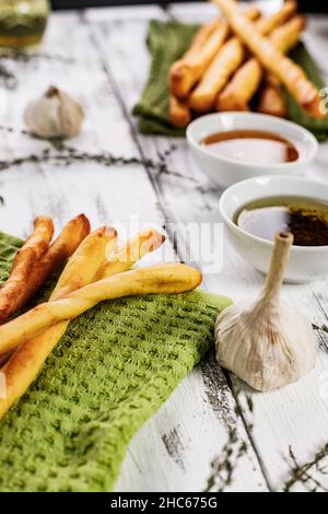 Knusprige Grissini-Brotstäbchen. Traditionelles italienisches Weizenbrot mit Knoblauch, Käse und Sesam. Essen Stillleben auf einem weißen rustikalen Hintergrund Stockfoto