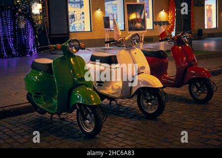 Foto der grünen, roten und weißen italienischen Vintage-Motorräder auf St. Deribasowskaja am Winterabend in Odessa Ukraine Stockfoto