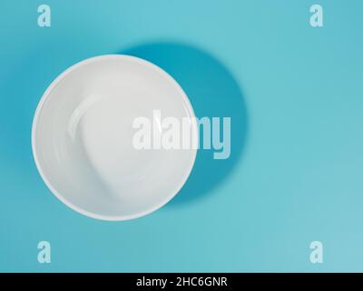 Leere weiße Schale auf blauem Hintergrund. Minimalistischer Stil. Stockfoto