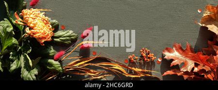 Orangefarbene Chrysanthemenblüten, trockenes Hasenschwanzgras und rote Eichenblätter. Herbstschmuck, Draufsicht mit Kopierraum. Flacher Lay auf dunklem Textil. Stockfoto