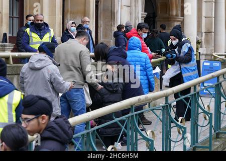 Die Menschen kommen an, um eine „Jingle Jab“-Impfimpfungs-Auffrischungsimpfung von Covid im Rathaus von Redbridge in Ilford, Essex, zu erhalten, da das Coronavirus-Auffrischungsprogramm am Weihnachtstag in ganz Großbritannien fortgesetzt wird. Bilddatum: Samstag, 25. Dezember 2021. Stockfoto