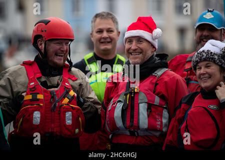 Weymouth, Großbritannien. 25th. Dezember 2021. Freiwillige Kajakfahrer beim jährlichen Weymouth Christmas Day Harbour Swim. Die Teilnehmer schwimmen über 70m zwischen den Ufern des Hafens von Weymouth und sammeln Geld für den Weymouth und den Portland Lions Club. Kredit: Liam Asman/Alamy Live Nachrichten Stockfoto