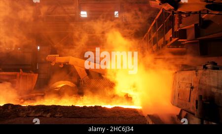 Heißer Stahl wird in die Rutsche im Stahlwerk gegossen, Schwerindustriekonzept. Produktion von geschmolzenem Stahl in Elektroöfen. Stockfoto