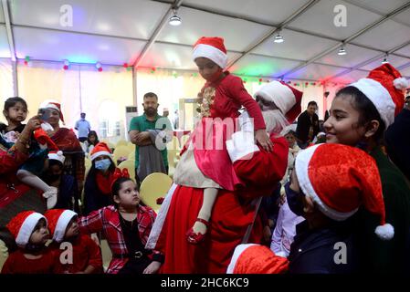 Dhaka, Bangladesch. 25th Dez 2021. Kinder posieren für ein Foto mit einem Mann, der als Weihnachtsmann gekleidet ist, während einer Weihnachtsfeier in der Hauptstadt Dhaka, Bangladesch, am 25. Dezember 2021. Kredit: Mamunur Rashid/Alamy Live Nachrichten Stockfoto