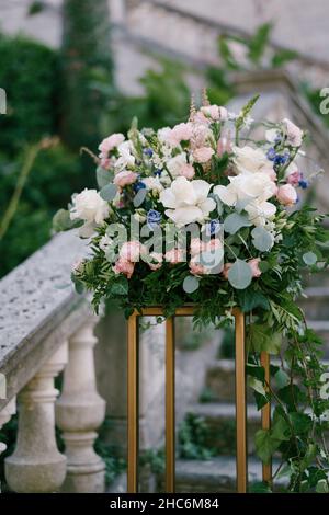 Blumenstrauß steht auf einem goldenen Sockel auf Steinstufen in der Nähe der Balustrade Stockfoto