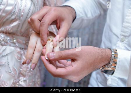 Der Bräutigam trägt einen Ring am Finger der Braut während der Trauung Stockfoto