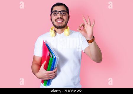 Junger Student mit Headset und Ordnern, zeigt OK Zeichen. Stockfoto