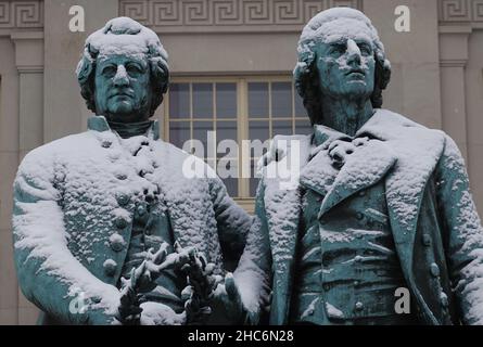 Weimar, Deutschland. 25th Dez 2021. Das Goethe-Schiller-Denkmal am Theaterplatz ist schneebedeckt. Die bronzene Doppelstatue vor dem Deutschen Nationaltheater wurde im 19th. Jahrhundert vom Dresdner Bildhauer E. Rietschel entworfen. Quelle: Soeren Stache/dpa-Zentralbild/dpa/Alamy Live News Stockfoto