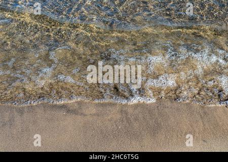 Schaumig klare Wellen am Strand. Kann den Seegrund sehen. Stockfoto