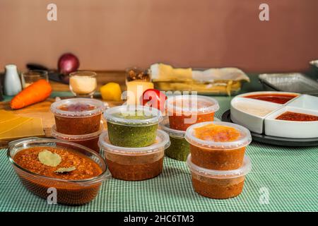 Verschiedene Gewürze in Einwegschalen und eine große Schüssel mit Bolognese-Sauce für die Zubereitung und Begleitung von Lasagne auf einem Tisch. Konzept von Pre Stockfoto