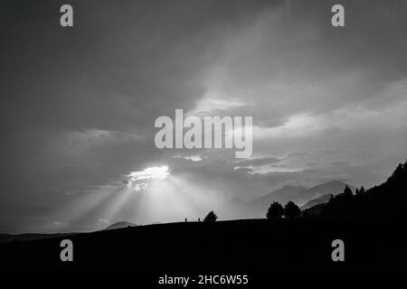Wunderschöne Graustufenansicht der Hügel, die unter dem wolkigen Himmel schimmern Stockfoto