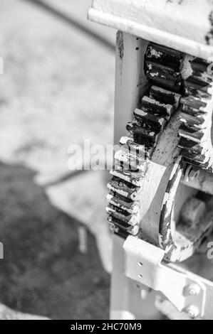 Vertikale Graustufenaufnahme von rostigen Zahnrädern Stockfoto