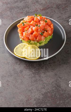 Köstliche Avocado- und gesalzene Lachstartare, serviert mit Zitrone, dunklem Hintergrund, selektiver Konzentration Stockfoto