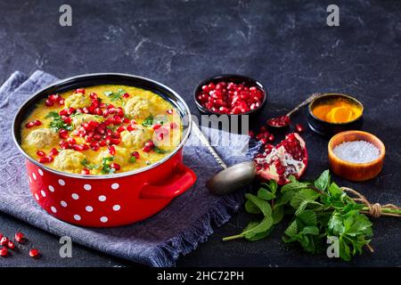 Ash-e Anar, Persian Split Pea Granatapfelsuppe mit Lamm Fleischbällchen in einem roten Topf auf einem Betontisch mit Zutaten horizontal von oben, schließen Stockfoto