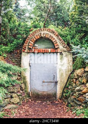 Eingang zu einem alten Ziegelbunker im Wald mit einer Metalltür Stockfoto