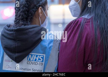 London, Großbritannien 25December 2021. NHS-Mitarbeiter und ehrenamtliche Mitarbeiter der Gemeinde verbringen ihren Weihnachtstag im Rathaus von Redbridge und bieten Coronavirus-Impfstoff und Jingle Jab für alle qualifizierten Personen als bestes Weihnachtsgeschenk seiner Art an. Sie schützen alle, da sich Omicron-Fälle alle zwei Tage verdoppeln. Quelle: Xiu Bao/Alamy Live News Stockfoto