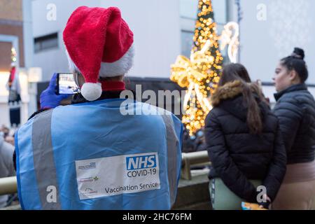 London, Großbritannien 25December 2021. NHS-Mitarbeiter und ehrenamtliche Mitarbeiter der Gemeinde verbringen ihren Weihnachtstag im Rathaus von Redbridge und bieten Coronavirus-Impfstoff und Jingle Jab für alle qualifizierten Personen als bestes Weihnachtsgeschenk seiner Art an. Sie schützen alle, da sich Omicron-Fälle alle zwei Tage verdoppeln. Quelle: Xiu Bao/Alamy Live News Stockfoto