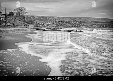 Schwarz-weiß-behandeltes Bild von Swanage am Strand an einem nassen Wintertag, behandelt wie eine alte Postkarte mit schaumig weißen Wellen Stockfoto