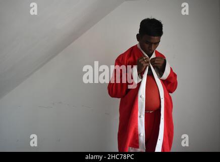 Kalkutta, Westbengalen, Indien. 25th Dez 2021. Krishna trägt das Weihnachtskleid vor seiner Vorstellung. Krishna Naskar, 18, ein Bahurupi-Künstler, der sich anlässlich der Weihnachtszeit in Kalkata wie ein Weihnachtsmann verkleidet hat. (Bild: © Sudipta das/Pacific Press via ZUMA Press Wire) Stockfoto