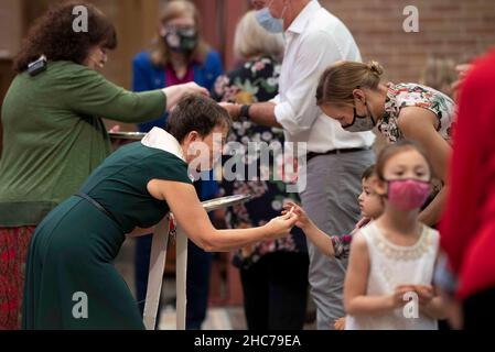 Austin, Texas, USA. 24th Dez 2021. Pastor ELLEN WILLIAMS überreicht einem Kind während der Weihnachtsfeier in der Lutherischen Kirche Saint Martin einen Kommunionwafer. Die Kirche, ein Mitglied der Evangelisch-Lutherischen Kirche von Amerika (ELCA), ist mehr als 136 Jahre alt und dient in ihrem modernen Gebäude aus der Mitte des Jahrhunderts in der Innenstadt von Austin, Texas, einer vielfältigen Bevölkerung. Kredit: Bob Daemmrich/Alamy Live Nachrichten Stockfoto