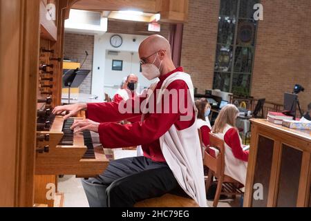 Austin, Texas, USA. 24th Dez 2021. Organist AUSTIN HALLER spielt während der Weihnachtsfeier in der Lutherischen Kirche Saint Martin vollständig maskiert. Die mehr als 136 Jahre alte Kirche dient in ihrem modernen Gebäude aus der Mitte des Jahrhunderts in der Innenstadt von Austin, Texas, einer vielfältigen Bevölkerung. Kredit: Bob Daemmrich/Alamy Live Nachrichten Stockfoto