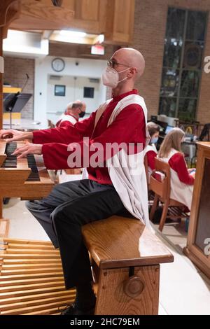 Austin, Texas, USA. 24th Dez 2021. Organist AUSTIN HALLER spielt während der Weihnachtsfeier in der Lutherischen Kirche Saint Martin vollständig maskiert. Die mehr als 136 Jahre alte Kirche dient in ihrem modernen Gebäude aus der Mitte des Jahrhunderts in der Innenstadt von Austin, Texas, einer vielfältigen Bevölkerung. Kredit: Bob Daemmrich/Alamy Live Nachrichten Stockfoto