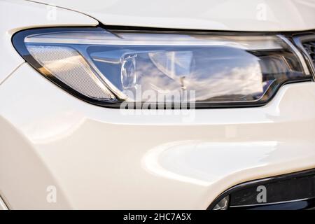 Ein Detail des rechten Scheinwerfers eines neuen weißen Autos Stockfoto