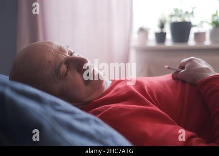 Der ältere Mann schlief morgens mit einem süßen Traum auf dem Bett im Schlafzimmer Stockfoto