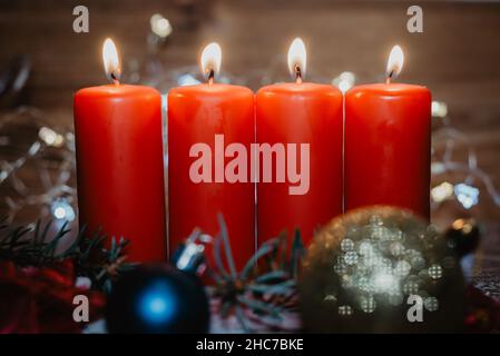 Vier rote Adventskerzen mit vier Kerzen angezündet und weihnachtsdekoration im Schnee als Vorlage Stockfoto