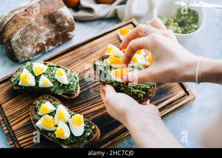 Kochen gesunder Bruschetta mit Guacamole und Hühnereiern auf dunklem Ciabatta-Brot. Stockfoto