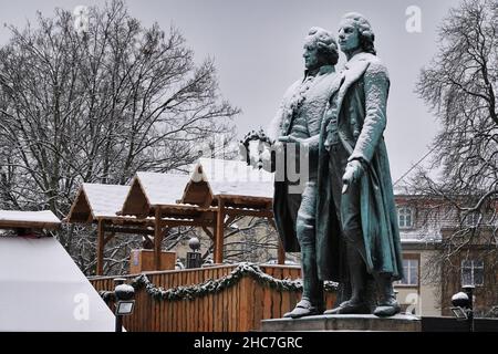 Weimar, Deutschland. 23rd Dez 2021. Das Goethe-Schiller-Denkmal am Theaterplatz ist schneebedeckt. Die bronzene Doppelstatue vor dem Deutschen Nationaltheater wurde im 19th. Jahrhundert vom Dresdner Bildhauer Ernst Rietschel entworfen. Quelle: Soeren Stache/dpa-Zentralbild/ZB/dpa/Alamy Live News Stockfoto