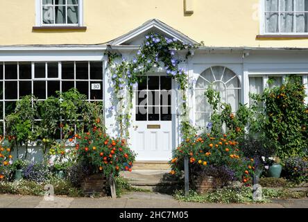 Schöne gelbe Hütte und Garten mit Blumen und Gemüse. Stockfoto