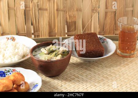 Sayur Lodeh oder Gemüse mit Kokosmilchsuppe. Traditionelle indonesische kulinarische Gerichte aus Java in einer traditionellen Schüssel, serviert auf dem Bamboo Table. Selektiv Stockfoto