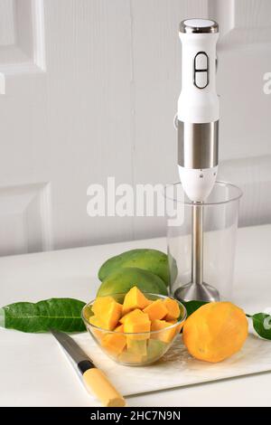 Zubereitung in der Küche: Mangosaft mit dem Handmixer machen. Zutaten und Utensilien sind fertig Stockfoto