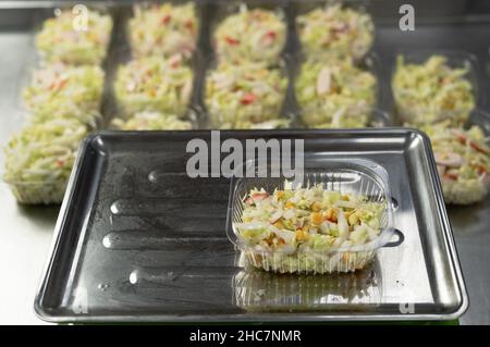 Der Koch bereitet das Essen im Restaurant zu und bereitet es in Einweggerichten zu. Platziert Einweg-Lunchboxen aus Kunststoff auf elektronische Geräte Stockfoto