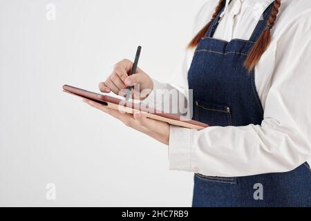 Zugeschnittenes Bild einer Kellnerin in Jeanschürze, die das Menü auf dem Tablet-Computer überprüft Stockfoto