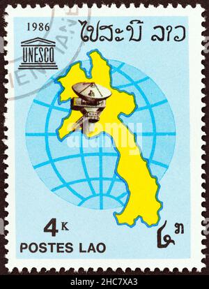 LAOS - UM 1986: Eine in Laos gedruckte Marke aus der Ausgabe '40th Anniversary of UNESCO' zeigt Laos-Karte, Erdstation und UNESCO-Emblem, um 1986. Stockfoto