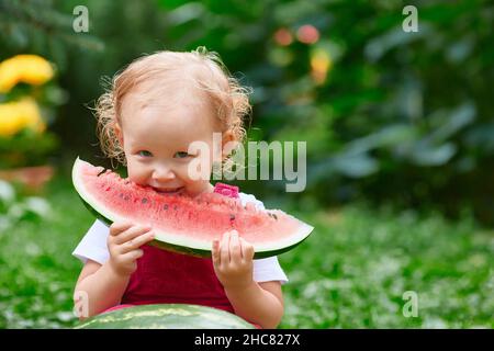 Lächelndes Kind isst im Sommer draußen Wassermelone. Speicherplatz kopieren. Stockfoto