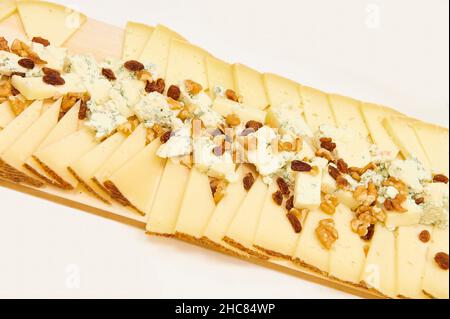 Tisch mit weißer Tischdecke, vorbereitet für die Gastronomie, mit verschiedenen Käseplatten mit Walnüssen und Rosinen Stockfoto