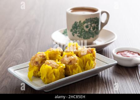 SIU Mai - Chinesische gedünstete Schweineknödel in Bambusdampfern. Stockfoto