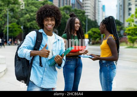 Lachend afro amerikanische männliche Student mit Gruppe von jungen Erwachsenen im Freien in der Stadt im Sommer Stockfoto